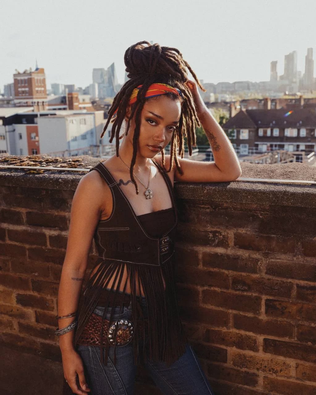 Model wearing the shell scarf as a head wrap on a rooftop
