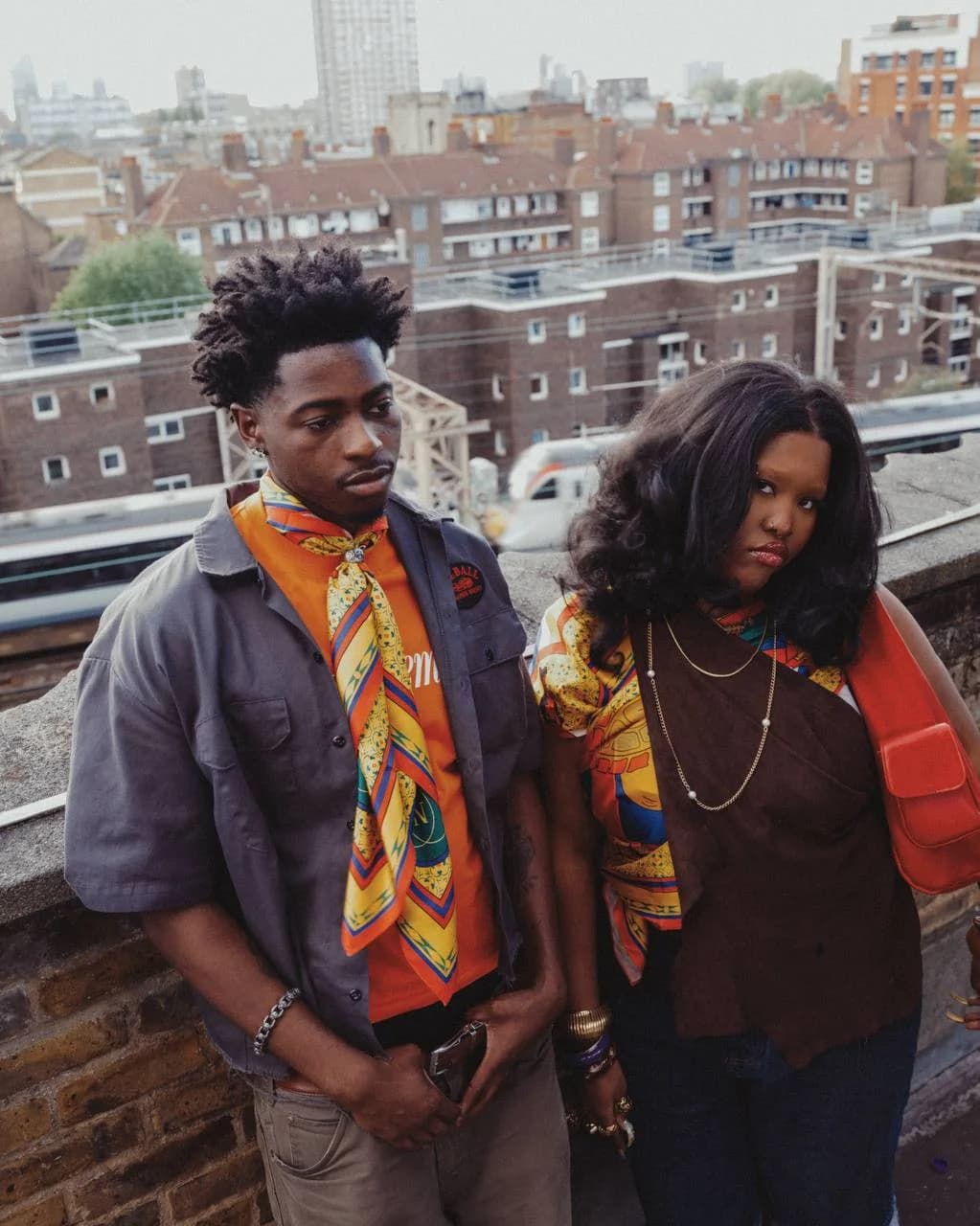 Two models styling the shell scarf with orange and brown outfits