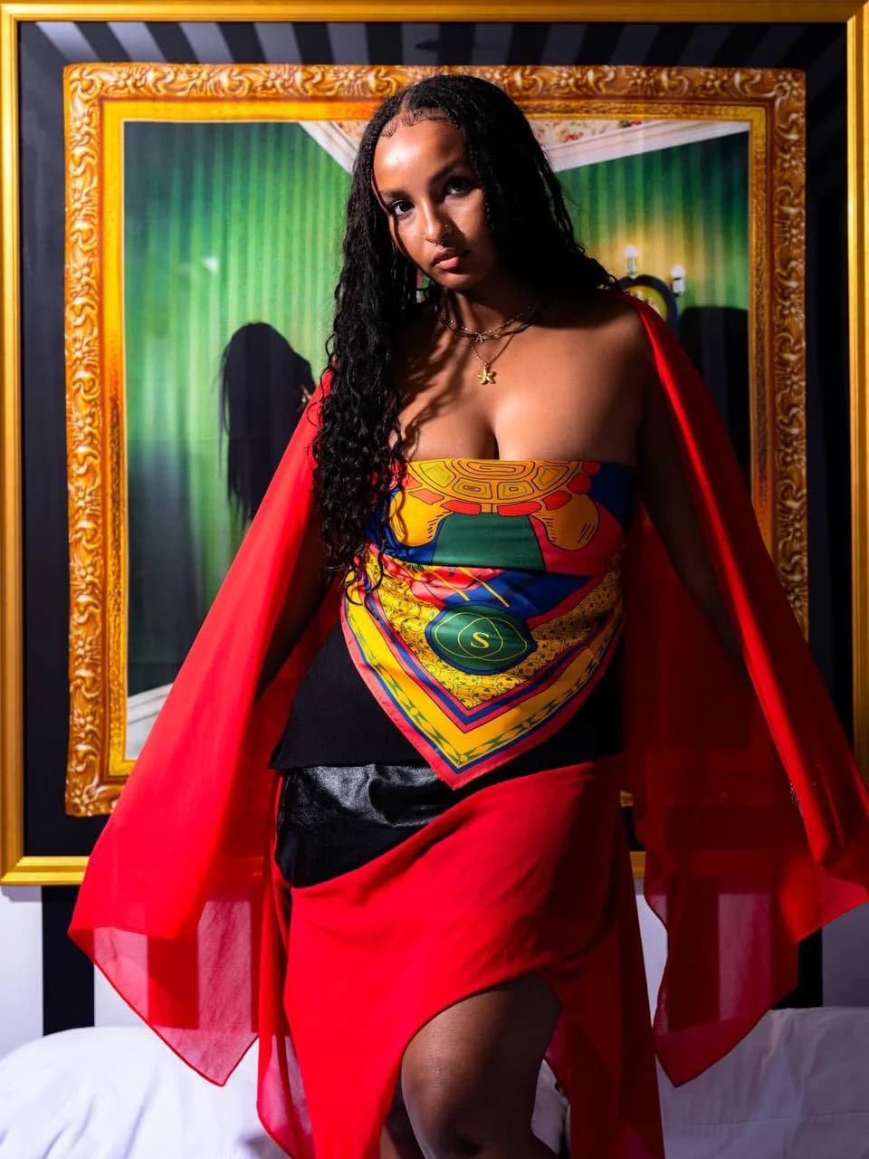 Model wearing the shell scarf with red styling in front of framed artwork