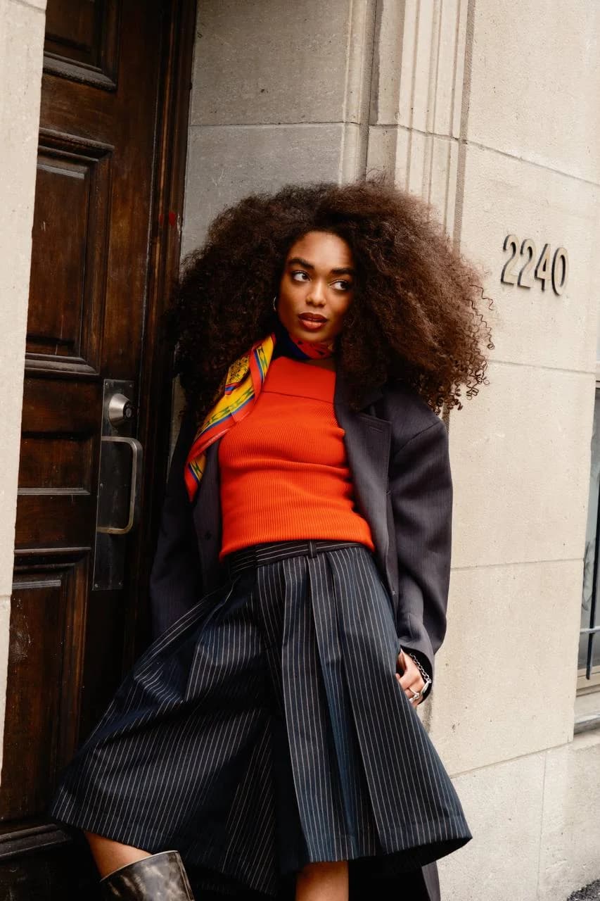 Model wearing the shell scarf at the neck with an orange top