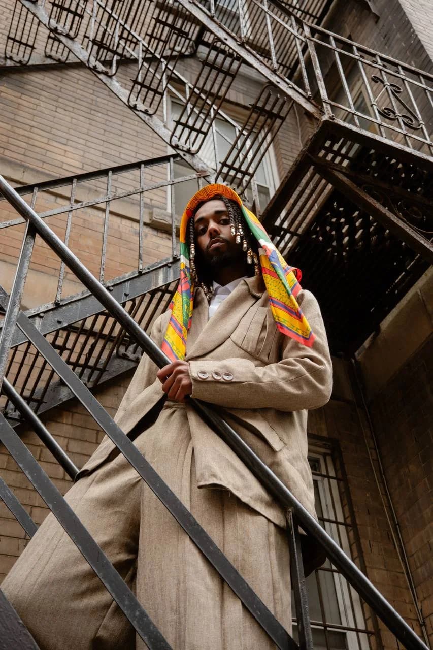 Model wearing the shell scarf as a hood on a metal stairway